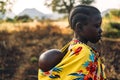 BOYA TRIBE, SOUTH SUDAN - MARCH 10, 2020: Girl in traditional colorful garment of Boya Tribe carrying baby on back on