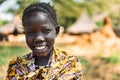 BOYA TRIBE, SOUTH SUDAN - MARCH 10, 2020: Girl in traditional colorful outfit and accessory smiling at camera against blurred