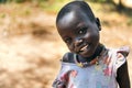BOYA TRIBE, SOUTH SUDAN - MARCH 10, 2020: Small girl in colorful dress and traditional necklace smiling at camera against blurred