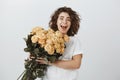 Boyfriend decided to surprise girlfriend with present. Good-looking amazed curly-haired female holding bucket of roses