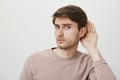 Boyfriend do not believe his couple and spying on her. Portrait of worried guy having trust issues, frowning and looking Royalty Free Stock Photo