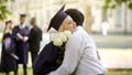 Boyfriend giving flowers to his graduate girlfriend and hugging special occasion Royalty Free Stock Photo