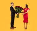 Boyfriend Giving Girlfriend Bouquet Of Red Roses Over Yellow Background Royalty Free Stock Photo