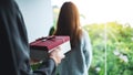 Boyfriend holding a gift box behind his girlfriend back to surprising her Royalty Free Stock Photo