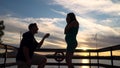 A boyfriend proposes to his pregnant girlfriend at sunset at sea