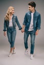 Boyfriend and smiling girlfriend in denim clothes holding hands and looking at each other