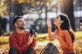 Boyfriend taking a picture of his girlfriend while she blows bubbles. Royalty Free Stock Photo