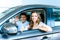 Boyfriend waving a hand, girlfriend showing thumb up sitting in a new car in showroom Royalty Free Stock Photo