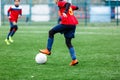 Boys in blue red sportswear plays football on field, dribbles ball. Young soccer players with ball on green grass. Training Royalty Free Stock Photo