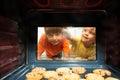 Boys brothers look though oven glass at cookies