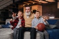 Boys on couch with their grandfather cheering for a basketball game and holding a basketball ball. Huge sports fanats. Royalty Free Stock Photo