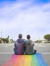 Boys couple sitting on the rainbow colored road. AI generated