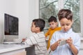 Boys enthusiastically draw on a computer using a tablet. The younger brother plays games on the phone