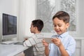 Boys enthusiastically draw on a computer using a tablet. The younger brother plays games on the phone