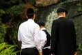 3 boys, a family of Hasidic Jews, in traditional clothes stand in front of a waterfall in the park in Uman, Ukraine