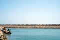 Boys fishing on the wave breaker of the marina on a calm day with flat sea and clear sky