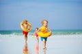 Boys and girl run with inflatable buoys doughnut, duck at beach Royalty Free Stock Photo