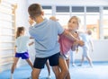 Boys and girls in gym perform basic elements of krav maga self-defense system.