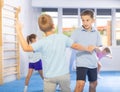 Boys and girls in gym perform basic elements of krav maga self-defense system.