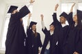 Multiracial students in mortarboard and bachelor gown raise their hands up to celebrate graduation. Royalty Free Stock Photo