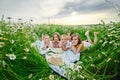 Boys and girls lie on a chamomile field. Children on a picnic in nature have fun among the flowers