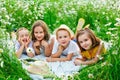 Boys and girls lie on a chamomile field. Children on a picnic in nature have fun among the flowers