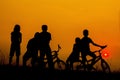 Boys and girls standing and sitting behind a bike with sunset Silhouette. Royalty Free Stock Photo