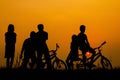 Boys and girls standing and sitting behind a bike with sunset Silhouette concept Royalty Free Stock Photo