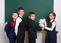 Boys giving girl flowers, elementary school child near blank chalkboard background, dressed in classic black suit, group pupil, ed