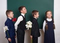 Boys giving girl flowers, elementary school child near blank chalkboard background, dressed in classic black suit, group pupil, ed