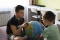 Boys with globe think where to go on vacation