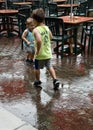 Boys playing in the rain next to empty tables during rain storm in St. Louise at Grand Farm Royalty Free Stock Photo