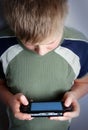 Boys hand playing portable video game Royalty Free Stock Photo