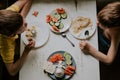 2 boys have breakfast, top view. Brothers at the table eat oatmeal and vegetables Royalty Free Stock Photo