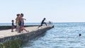 Boys jumping off a stone jetty as some school children go back to school