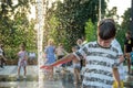 Boys jumping in water fountains. Children playing with a city fountain on hot summer day. Happy friends having fun in fountain. Royalty Free Stock Photo