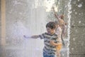 Boys Jumping In Water Fountains. Children Playing With A City Fountain On Hot Summer Day. Happy Friends Having Fun In Fountain.