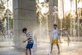 Boys jumping in water fountains. Children playing with a city fountain on hot summer day. Happy friends having fun in fountain. Royalty Free Stock Photo