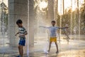 Boys jumping in water fountains. Children playing with a city fountain on hot summer day. Happy friends having fun in fountain. Royalty Free Stock Photo