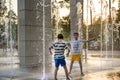 Boys jumping in water fountains. Children playing with a city fountain on hot summer day. Happy friends having fun in fountain. Royalty Free Stock Photo