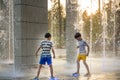 Boys jumping in water fountains. Children playing with a city fountain on hot summer day. Happy friends having fun in fountain. Royalty Free Stock Photo