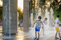 Boys jumping in water fountains. Children playing with a city fountain on hot summer day. Happy friends having fun in fountain. Royalty Free Stock Photo