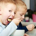 Boys kids children eating corn flakes breakfast meal at the table Royalty Free Stock Photo