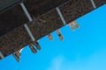 Boys legs in shoes hanging from the bridge against blue sky