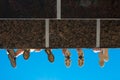 Boys legs in shoes hanging from the bridge against blue sky