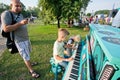 Boys making music & playing piano on a green playground