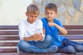 Boys with mobile phone sitting on the bench outdoors Royalty Free Stock Photo