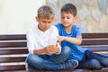 Boys with mobile phone sitting on the bench outdoors Royalty Free Stock Photo