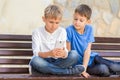 Boys with mobile phone sitting on the bench outdoors Royalty Free Stock Photo