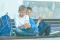 Boys with mobile phone sitting on the bench outdoors Royalty Free Stock Photo